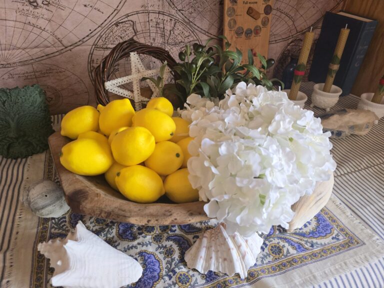 A Summer Solstice Altar with a bowl full of lemons, olive branches, and white hydrangea flowers