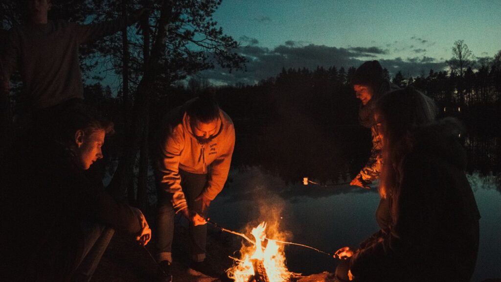 A group roasting marshmallow around a fire