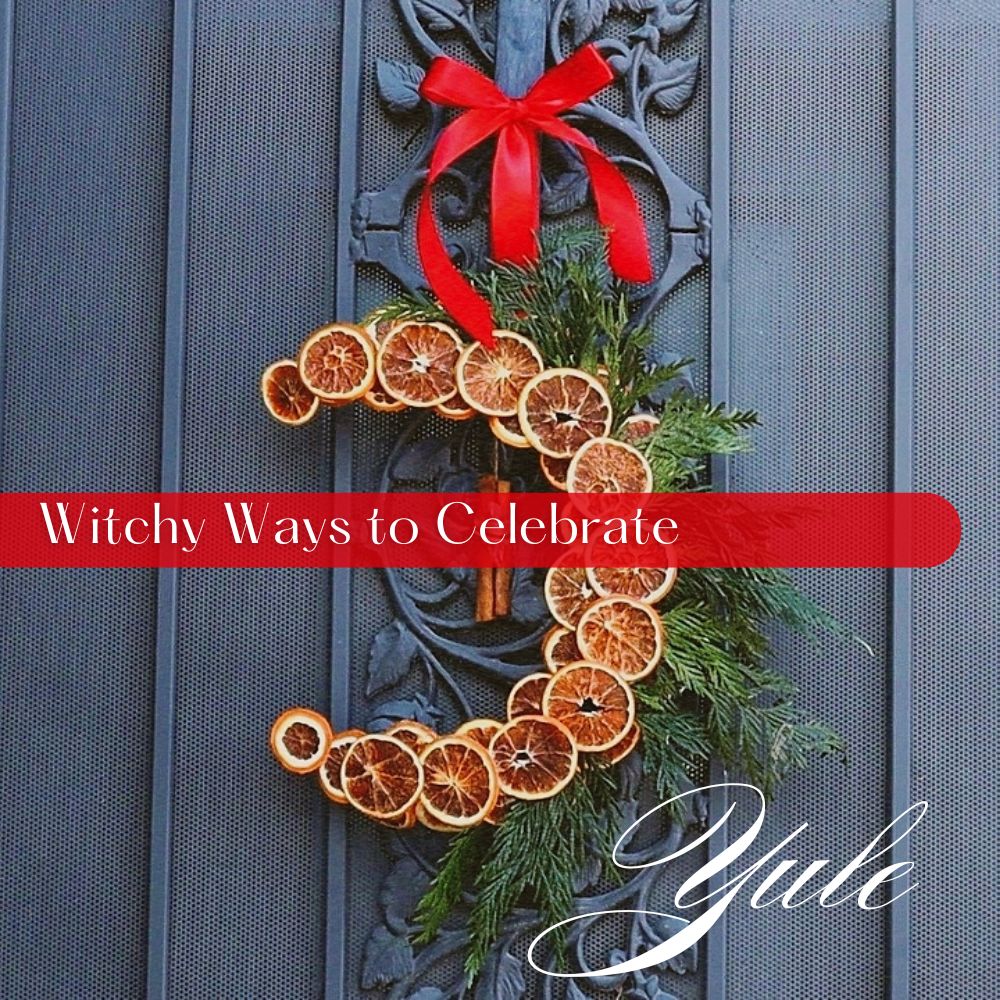 A crescent-shaped Yule wreath made of dried orange slices, evergreen sprigs, and cinnamon sticks, tied with a red ribbon on a black iron door — symbolizing the Winter Solstice and Green Witchcraft traditions.